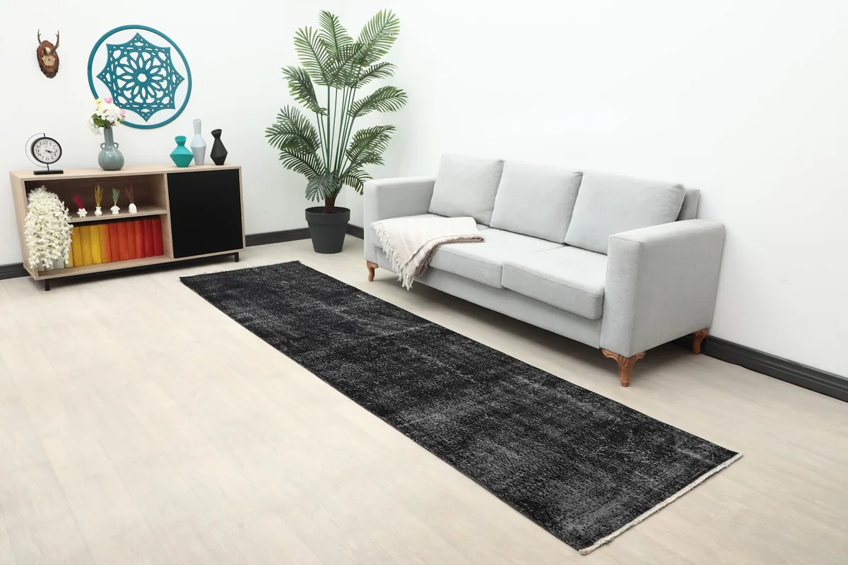 Long view of the black runner rug in a living space with a gray sofa and plants