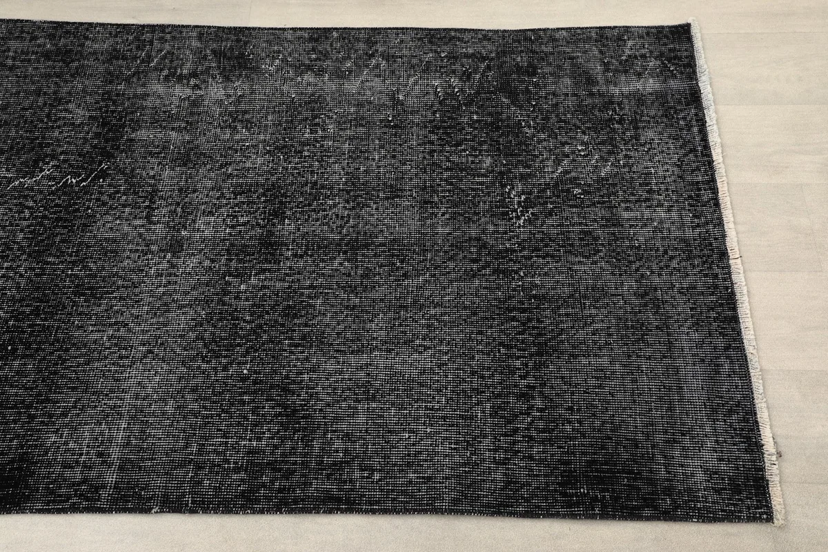 Mid-section close-up of the black distressed rug, highlighting its aged appearance