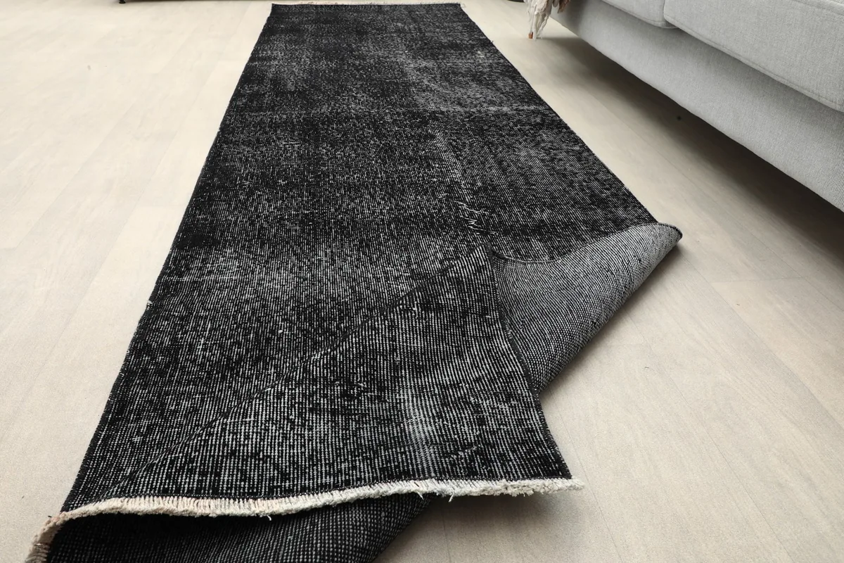The runner rug partially rolled, demonstrating its flexibility and thickness