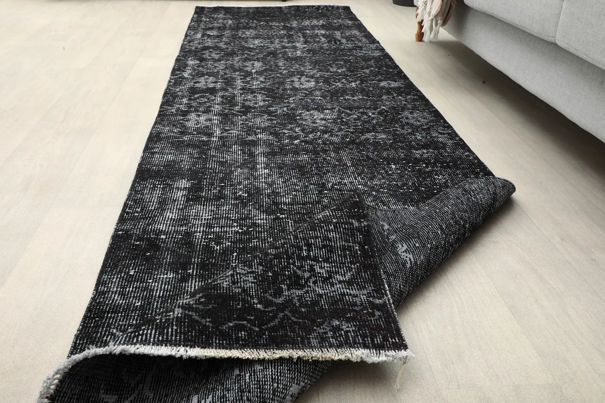 Runner rug partially unrolled in a room, showing its length and how it lays flat.