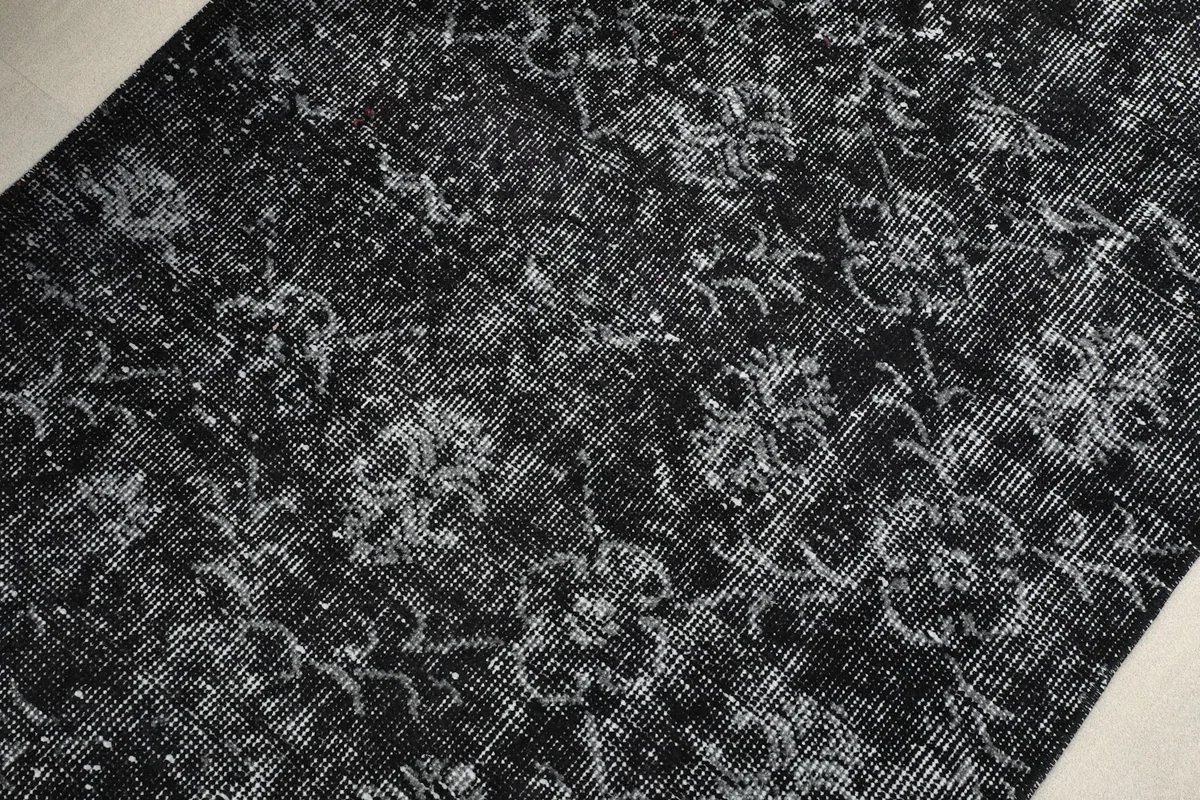 Close-up detail of the hand-knotted wool pile, revealing the intricate geometric motifs and black and gray tones.