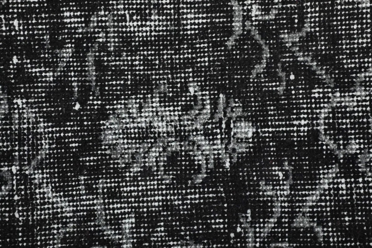 Extreme close-up of the rug's surface, showing the tight knotting and texture of the distressed wool.