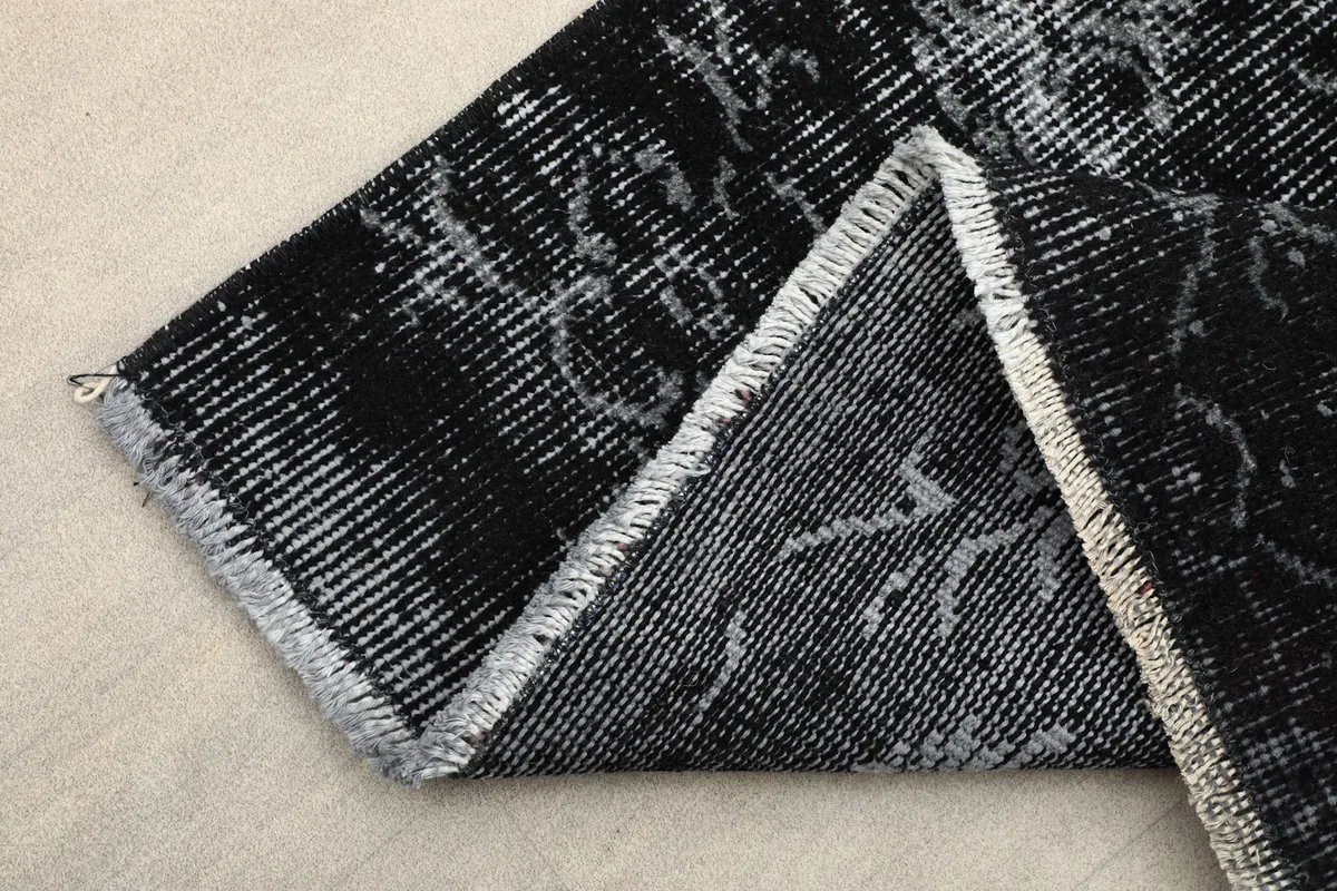 Folded corner of the rug, displaying the thickness of the pile and the cotton foundation.