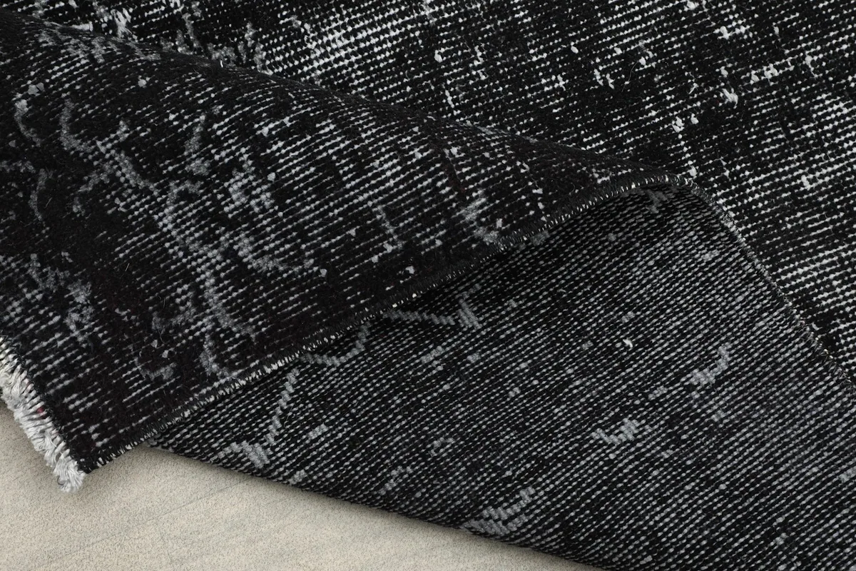 Partially rolled rug, illustrating its flexibility and the consistent black and gray pattern.