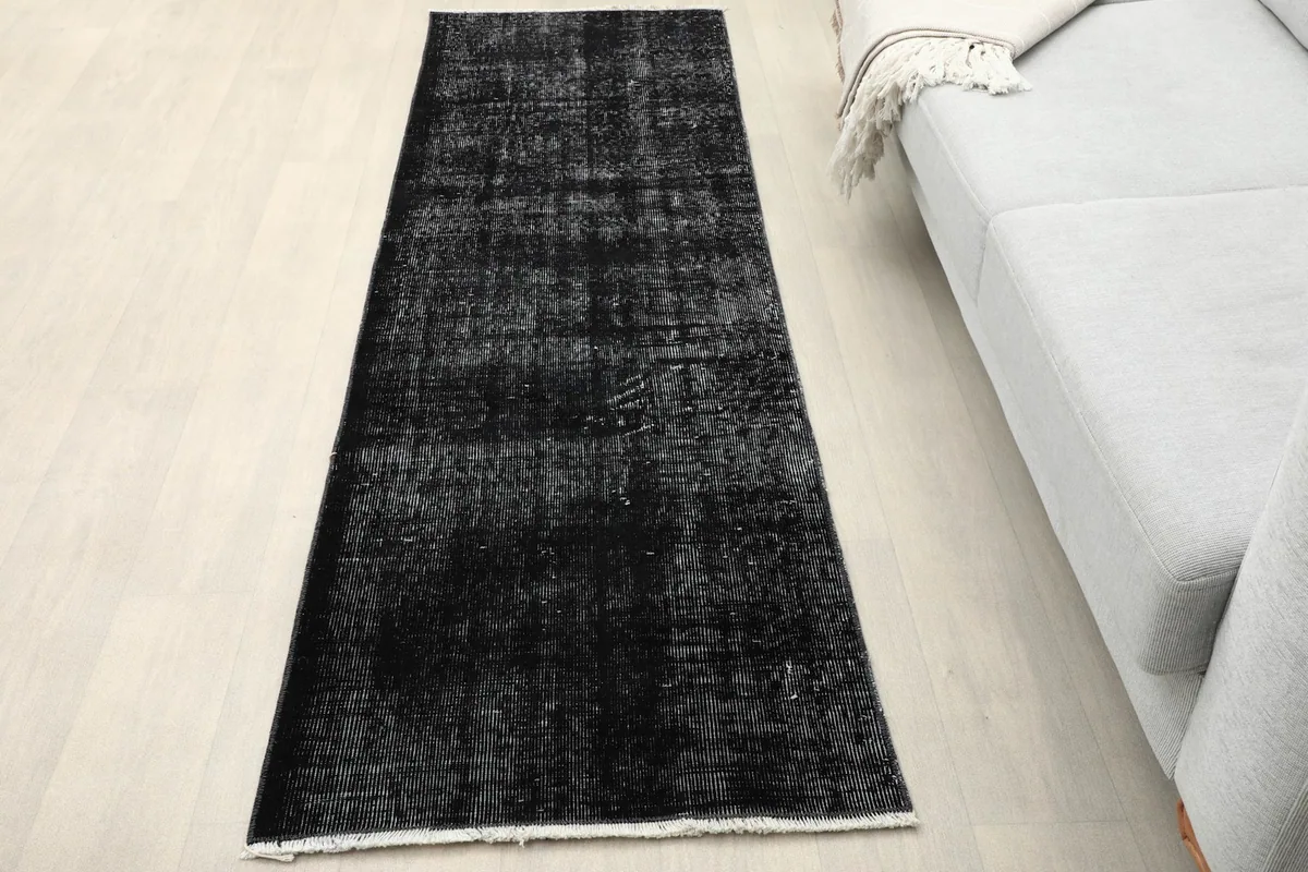 Charcoal runner rug placed in a room next to a light gray sofa
