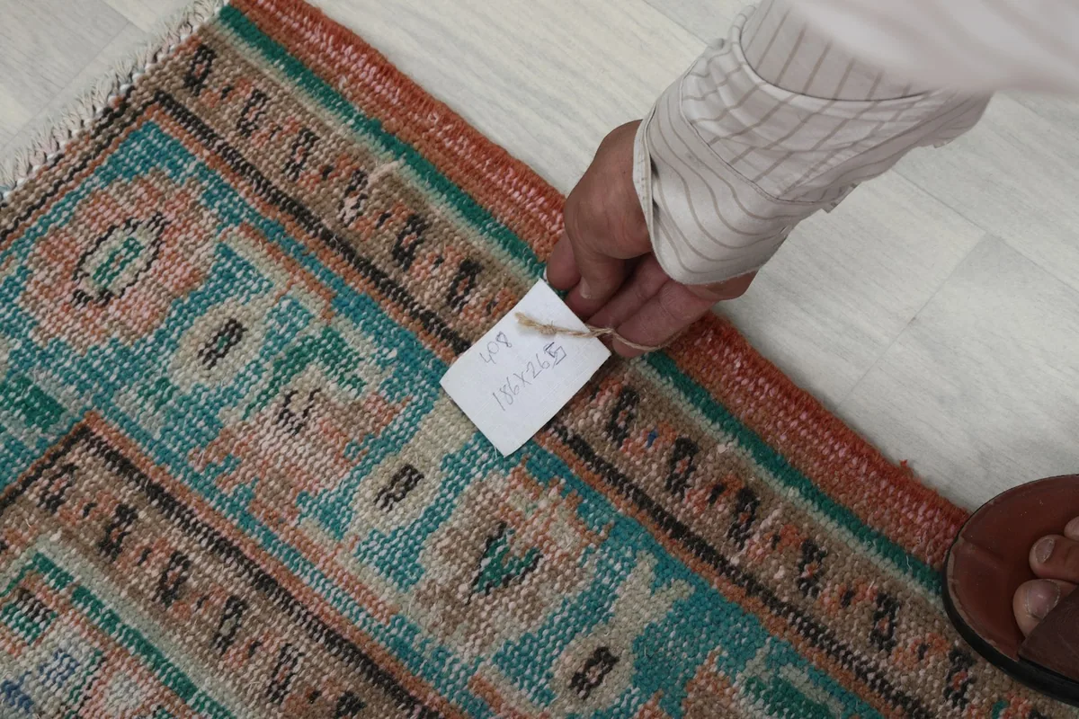 Hand holding a tag with the rug's size and dimensions
