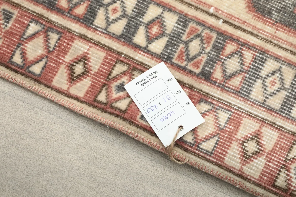 Close-up of the rug's border with a product tag, indicating its vintage origin and material.