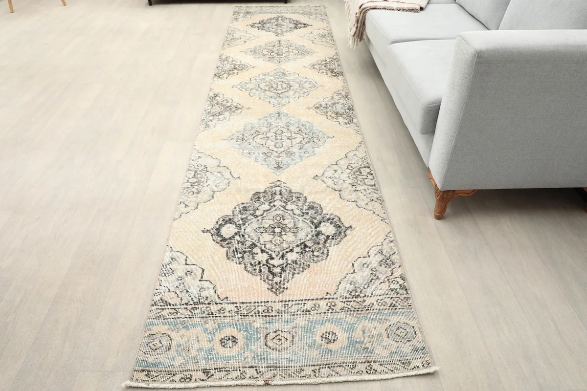Vintage Anatolian runner rug in a long hallway next to a light gray sofa
