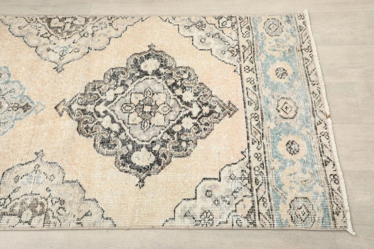 Close-up of a gray medallion motif and the blue border on the runner rug