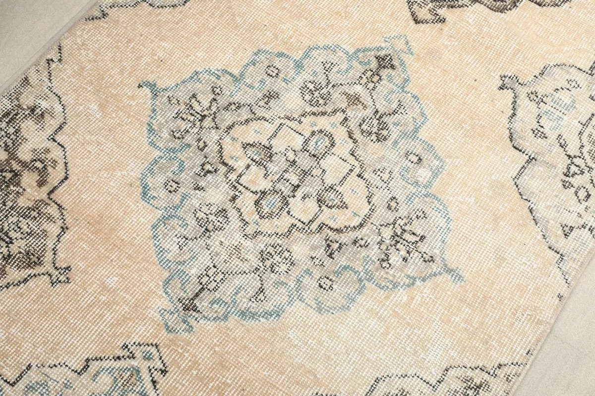 Close-up of a faded blue and beige medallion with intricate geometric details