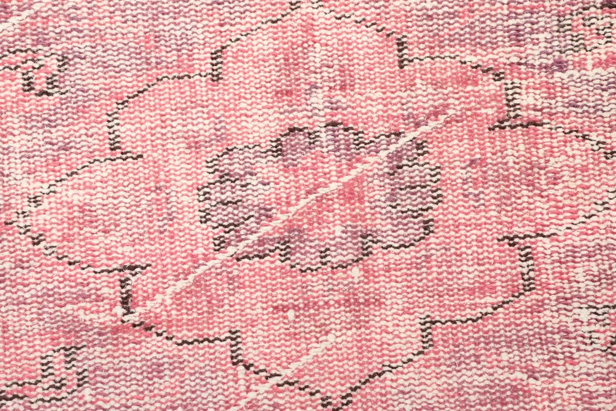 Detailed view of a central medallion motif with faded rose and charcoal tones
