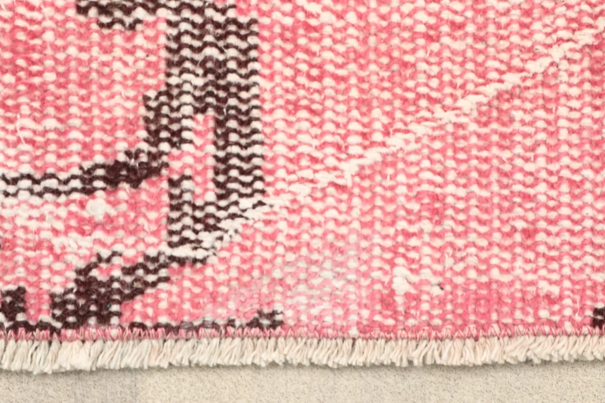 Close-up of the fringe and edge of the hand-knotted rose wool rug