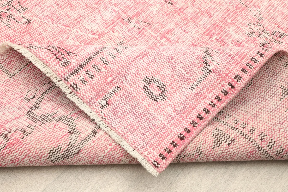 Folded corner of the rug showing the back of the cotton foundation and the wool pile