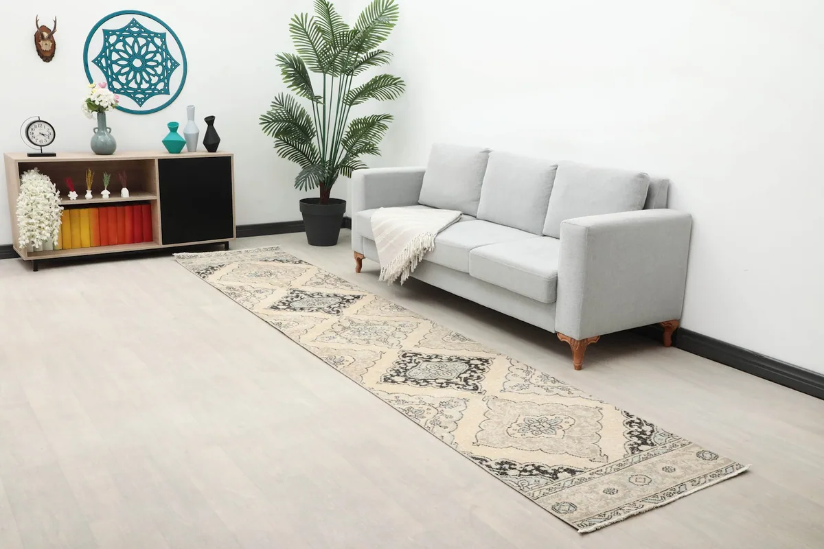 Long view of the ivory and charcoal runner rug in a room with a sofa and decor, highlighting its scale