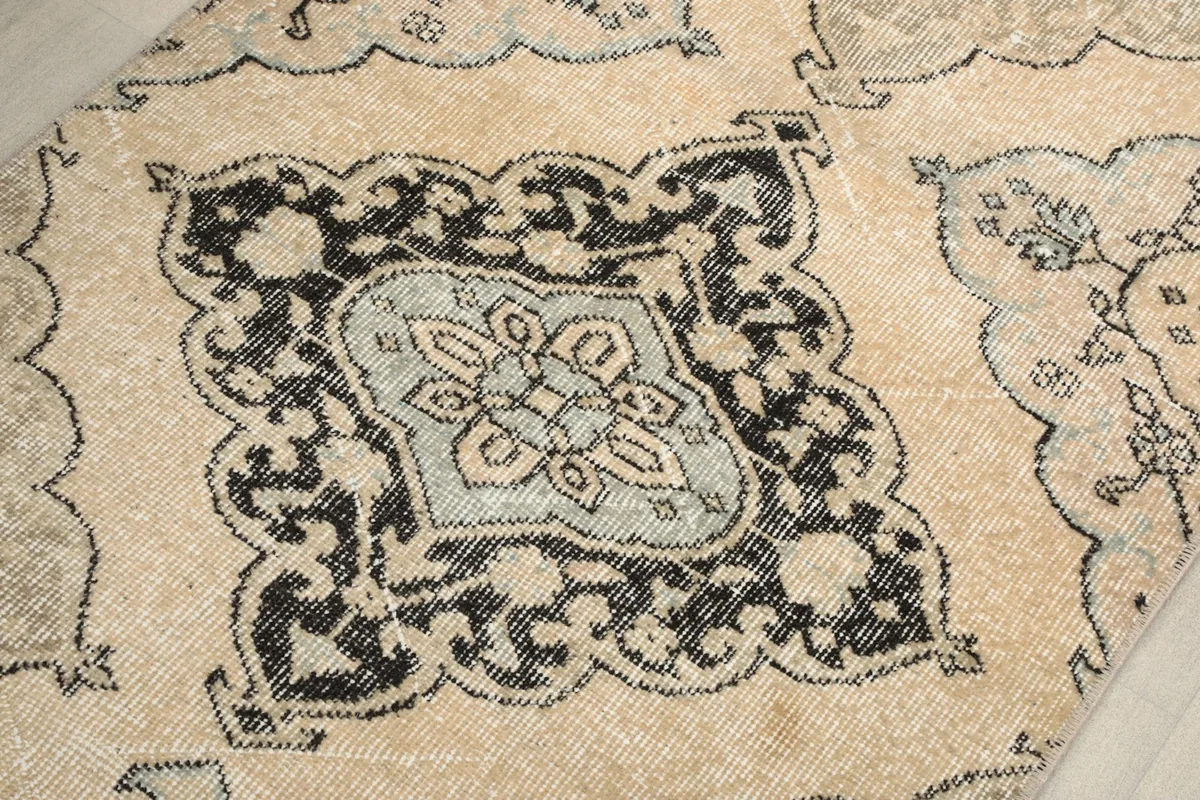 Close inspection of a charcoal and gray medallion against the ivory field, revealing texture