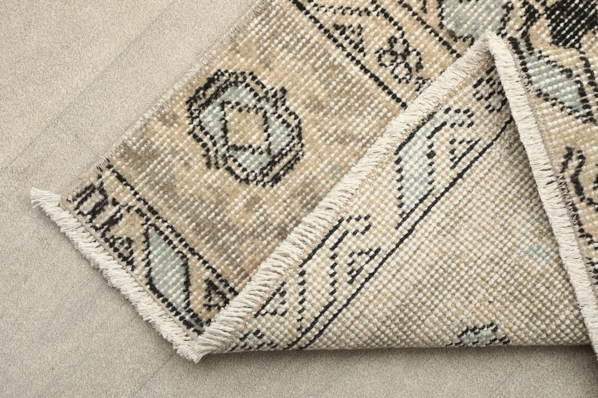 Corner of the rug folded to reveal the cotton foundation and reverse side of the hand-knotted construction