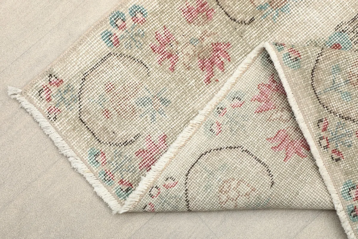 Corner of the rug folded to reveal the cotton foundation and the reverse side of the hand-knotted wool pile.