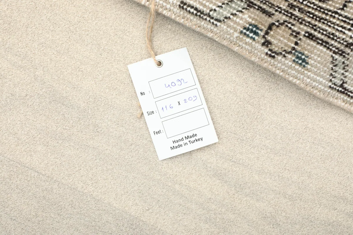 Product tag for the rug, showing the size 116x209 cm and 'Hand Made in Turkey'.