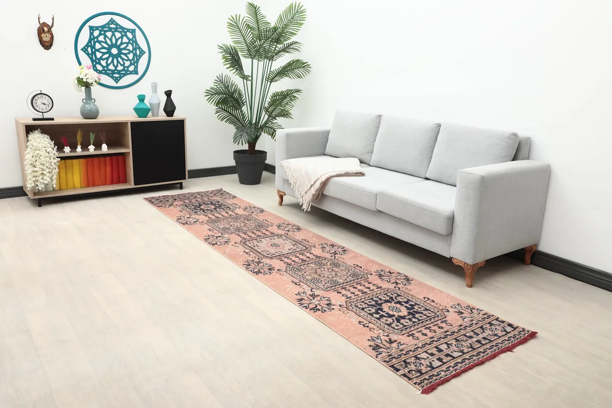 Vintage Anatolian runner rug in a room setting, showcasing its length and rose and navy geometric design.