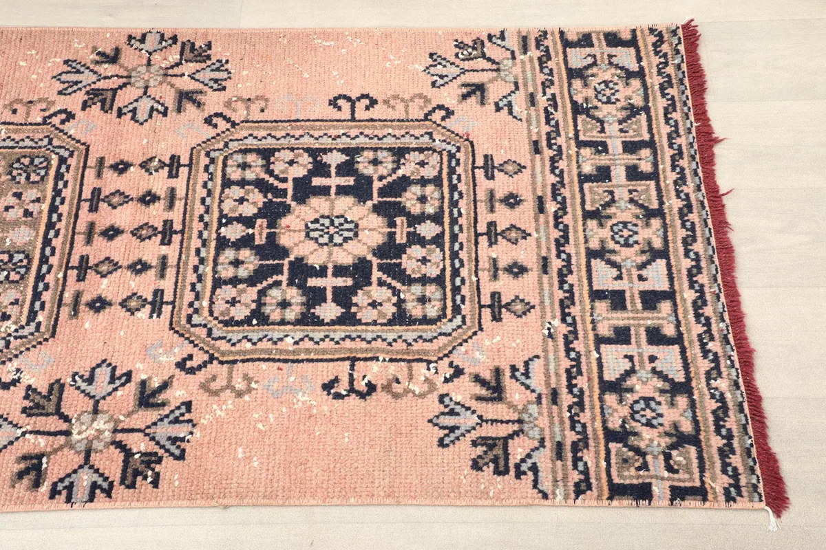 Close-up detail of the rose field and navy geometric motif near one end of the runner rug.