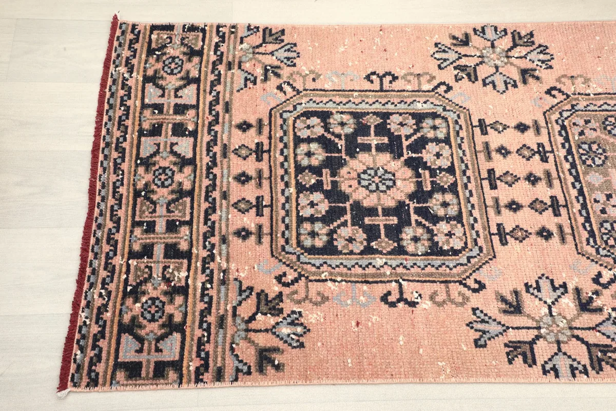 Detailed view of the repeating navy geometric patterns and border design on the vintage rose runner.