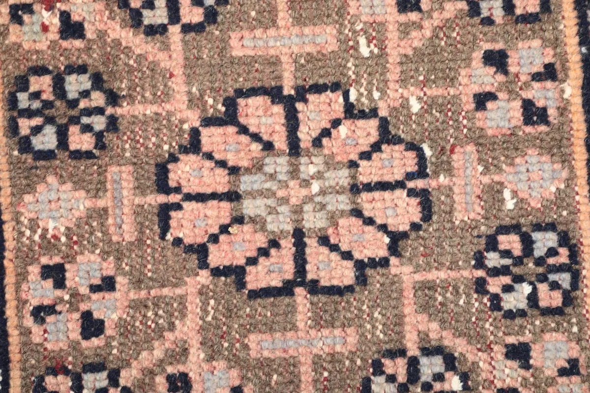 Extreme close-up showing the texture of the low wool pile and the hand-knotted details of the rug.