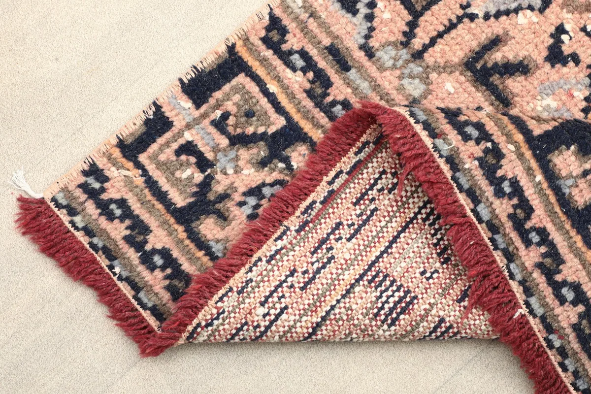 Folded corner of the runner rug, revealing the tight weave of the wool pile and cotton foundation.