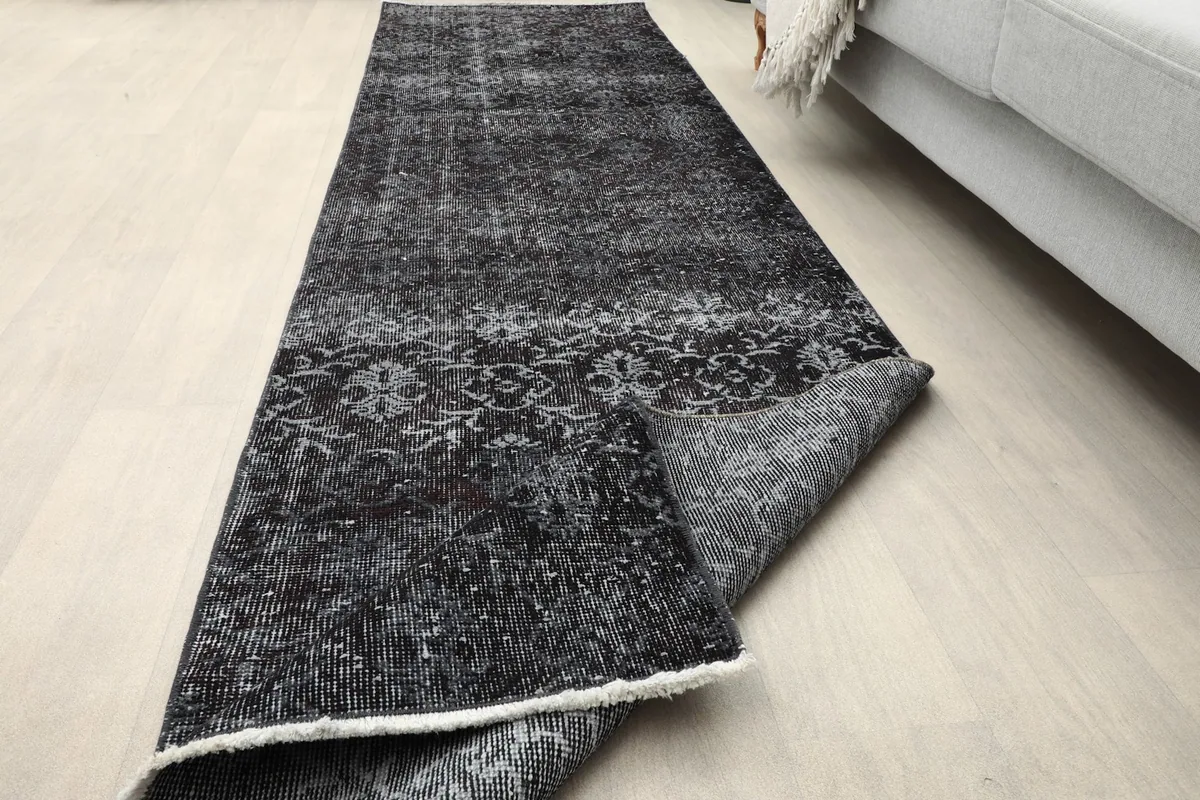 Runner rug partially unrolled on the floor, showcasing its length and the reverse side