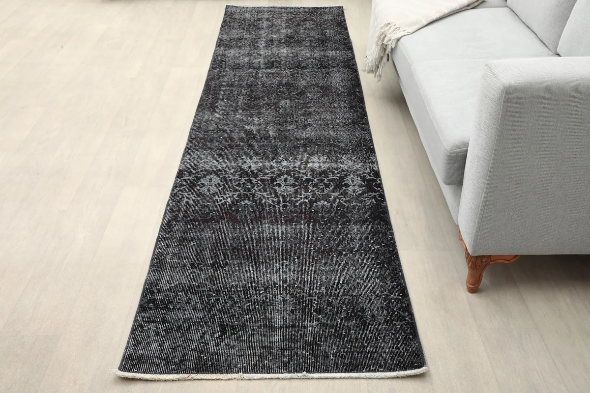 Runner rug laid out in a living room setting next to a gray sofa, showing its full length