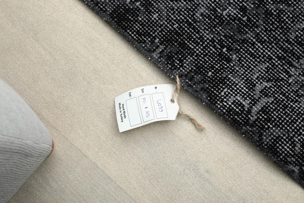 A close-up of the rug's label, indicating its origin and materials, attached to the corner