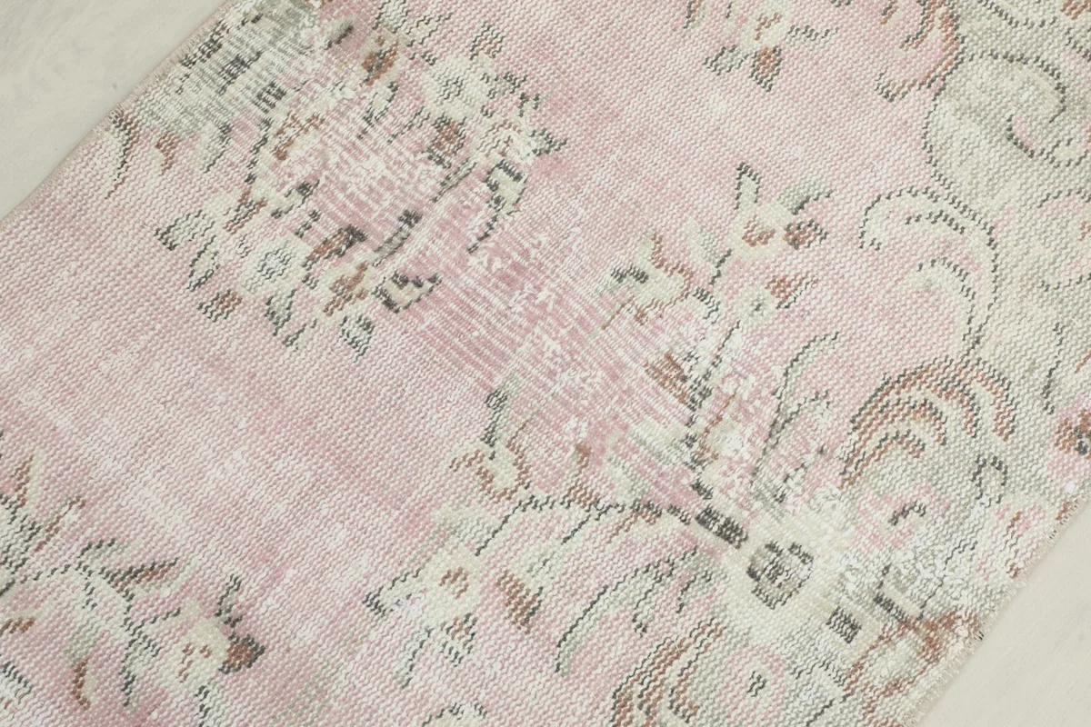 Close-up of the rug's central field, showing the soft rose tones and subtle wear on the wool pile