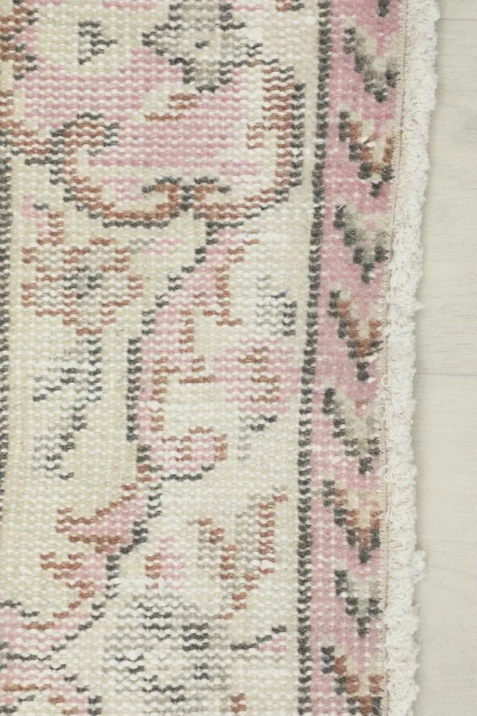 Detail of the rug's edge and fringe, showcasing the border pattern and the hand-knotted construction