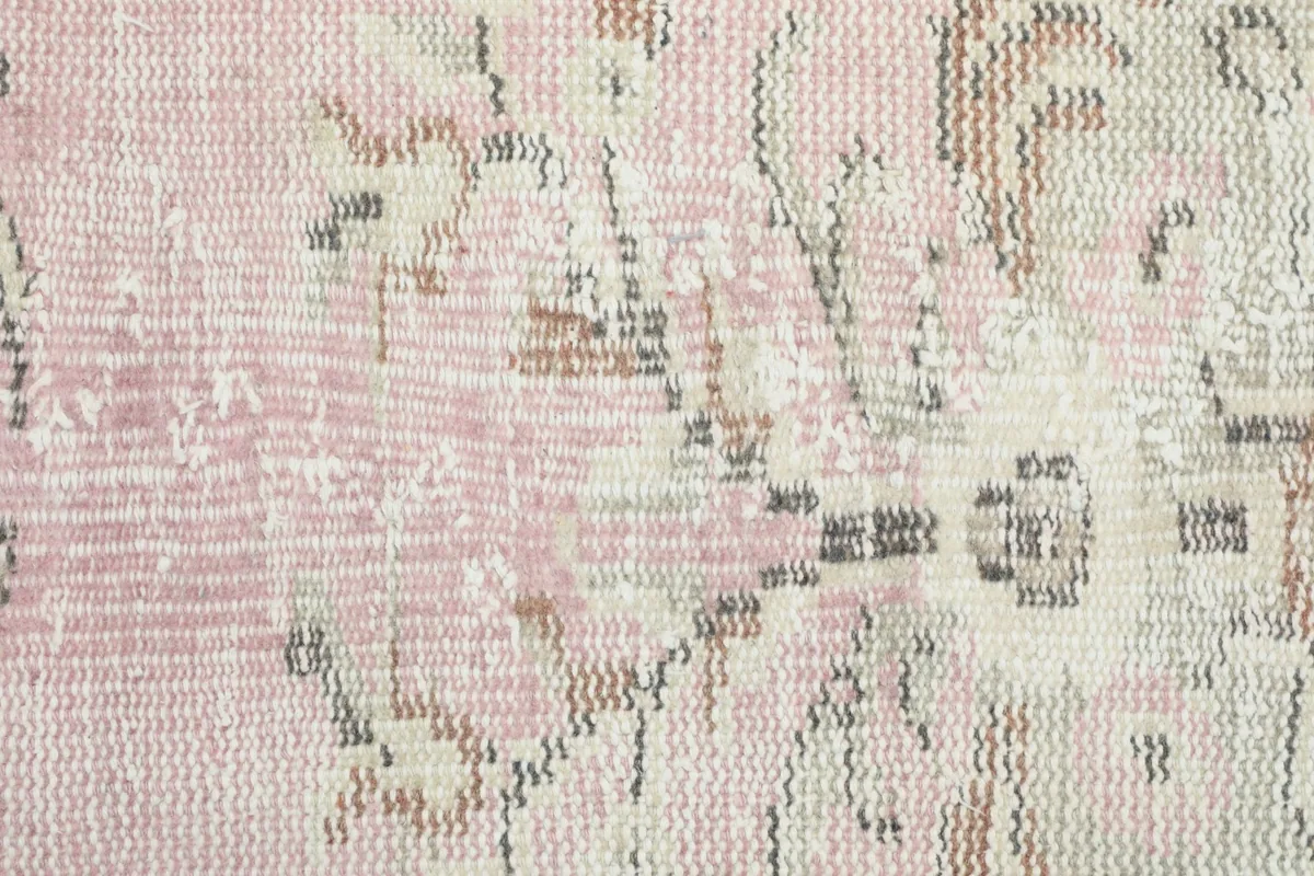 Extreme close-up of the low wool pile, revealing the weave and distressed texture of the vintage rug