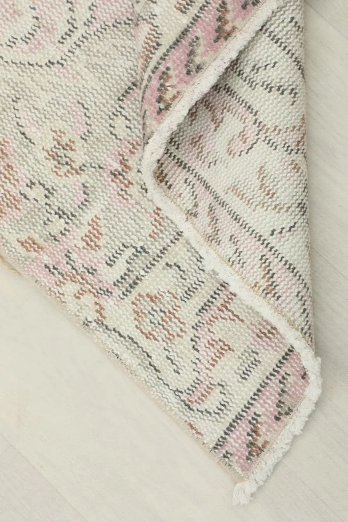 The corner of the rug folded back, showing the cotton foundation and the reverse side of the knots