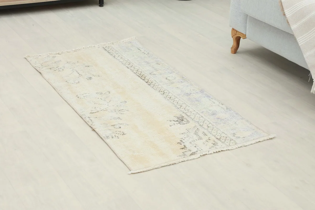Overhead view of the vintage rug showcasing its faded ivory and beige colors with tribal patterns