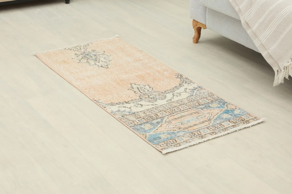 Angled view of the rust and blue vintage rug, showing its full length and patterns