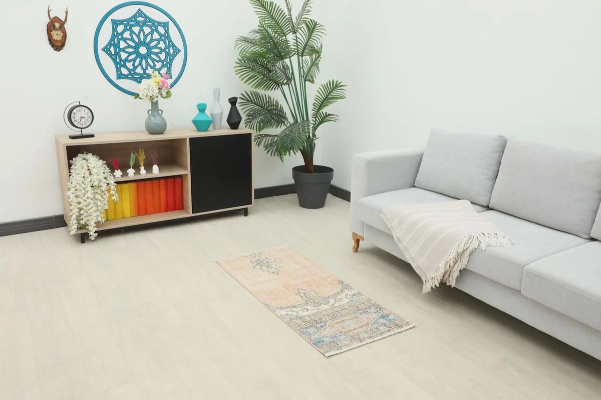Vintage Anatolian rug placed in a living room setting with a light gray couch and wooden cabinet