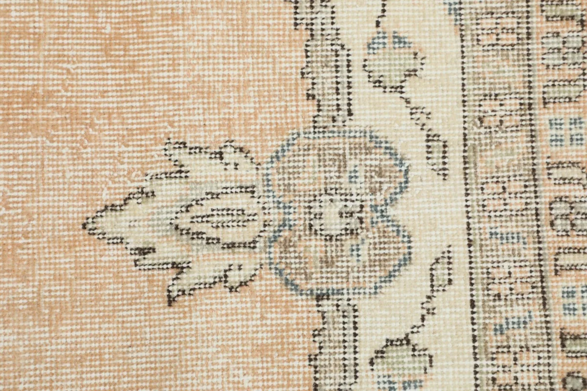 Close-up of the intricate floral and leaf patterns on the ivory and rust rug field