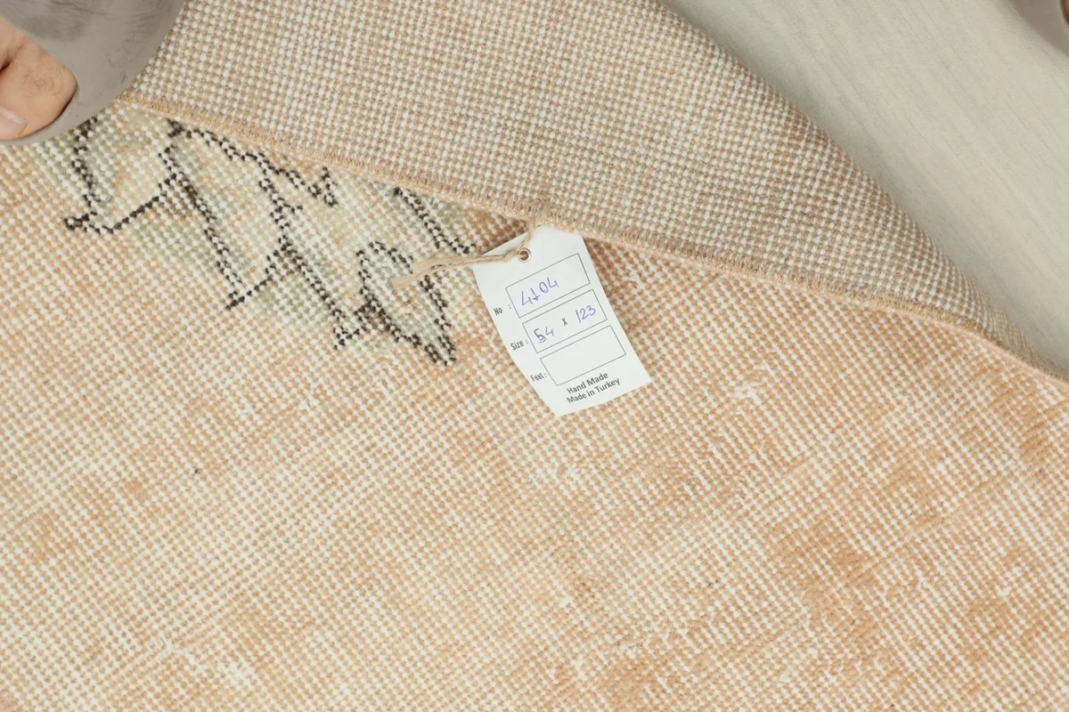 View of the rug's back with a product tag, showing the wool knots on cotton foundation