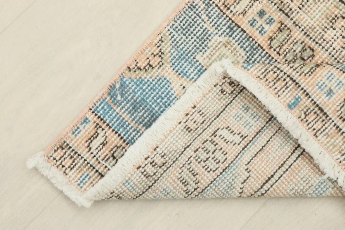 Corner of the vintage rug folded to reveal the back, showing the cotton foundation