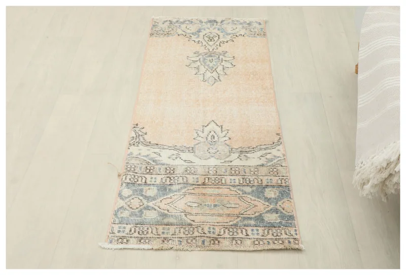 Full top view of the 1'9" x 4'6" beige and blue vintage Anatolian runner rug on a white floor.