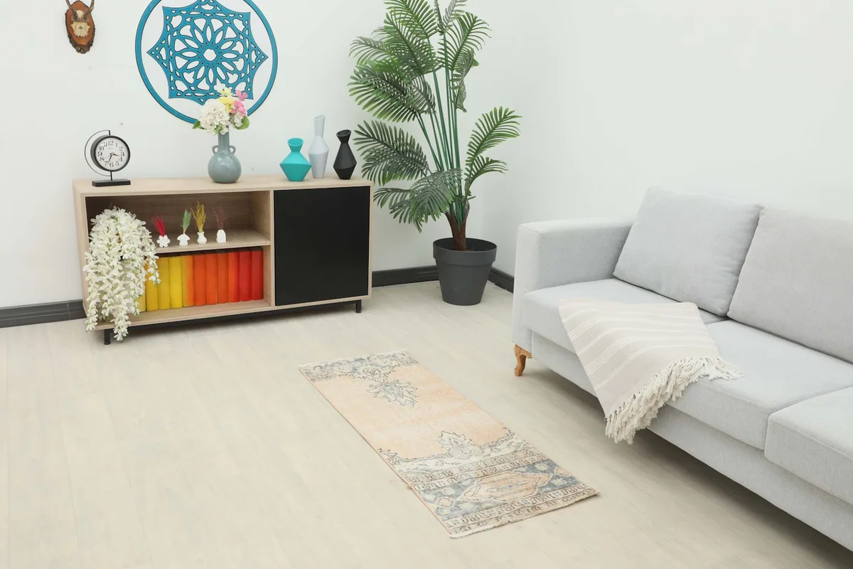 Beige and blue runner rug in a modern living space next to a sofa and cabinet, showing scale.