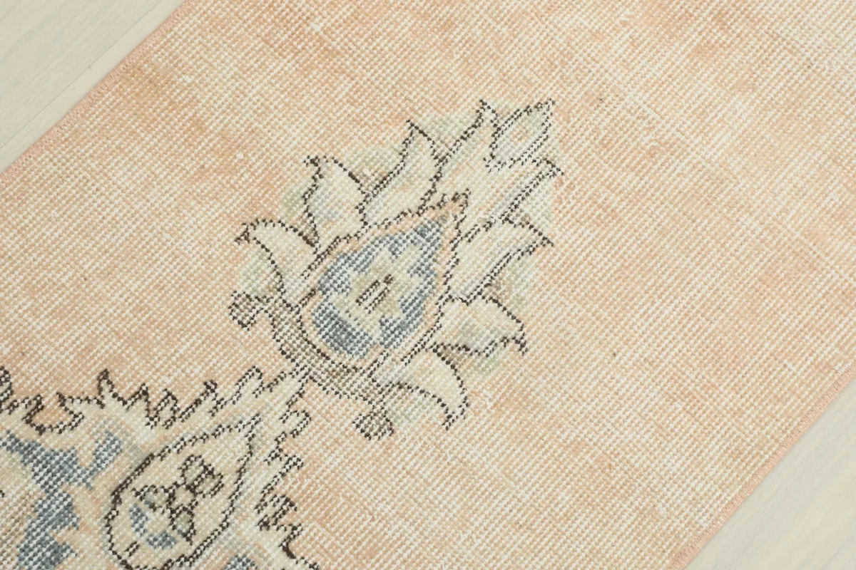 Tight close-up of a central blue and cream floral motif with intricate details and slight wear.
