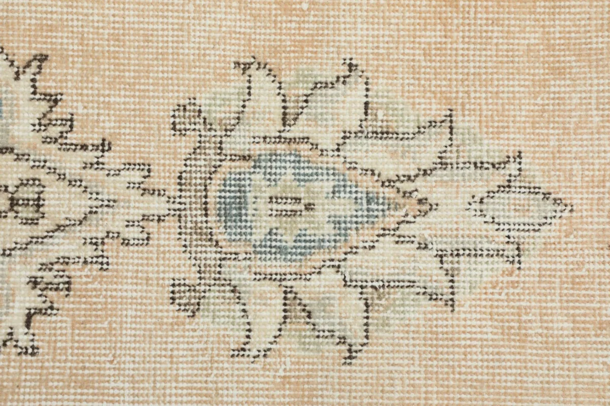 Close-up showing the texture and colors of a floral design, with beige background and blue accents.