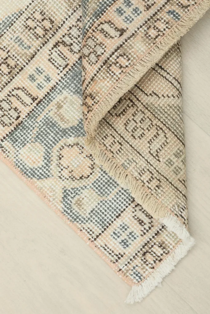 Corner of the rug folded to show the hand-knotted wool pile and cotton foundation from the back.