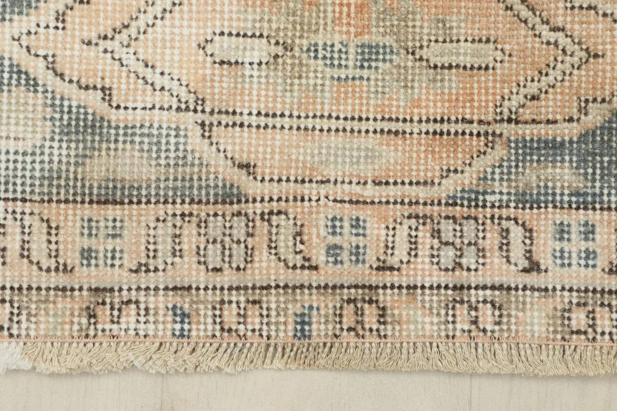 Detailed view of the rug's fringe and the intricate geometric patterns along the border.