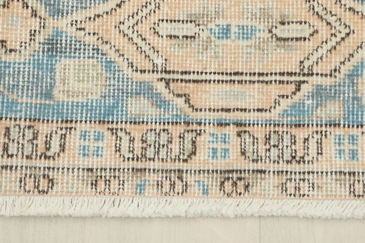 Close-up of the rug's border and fringe, highlighting the hand-knotted construction and patterns