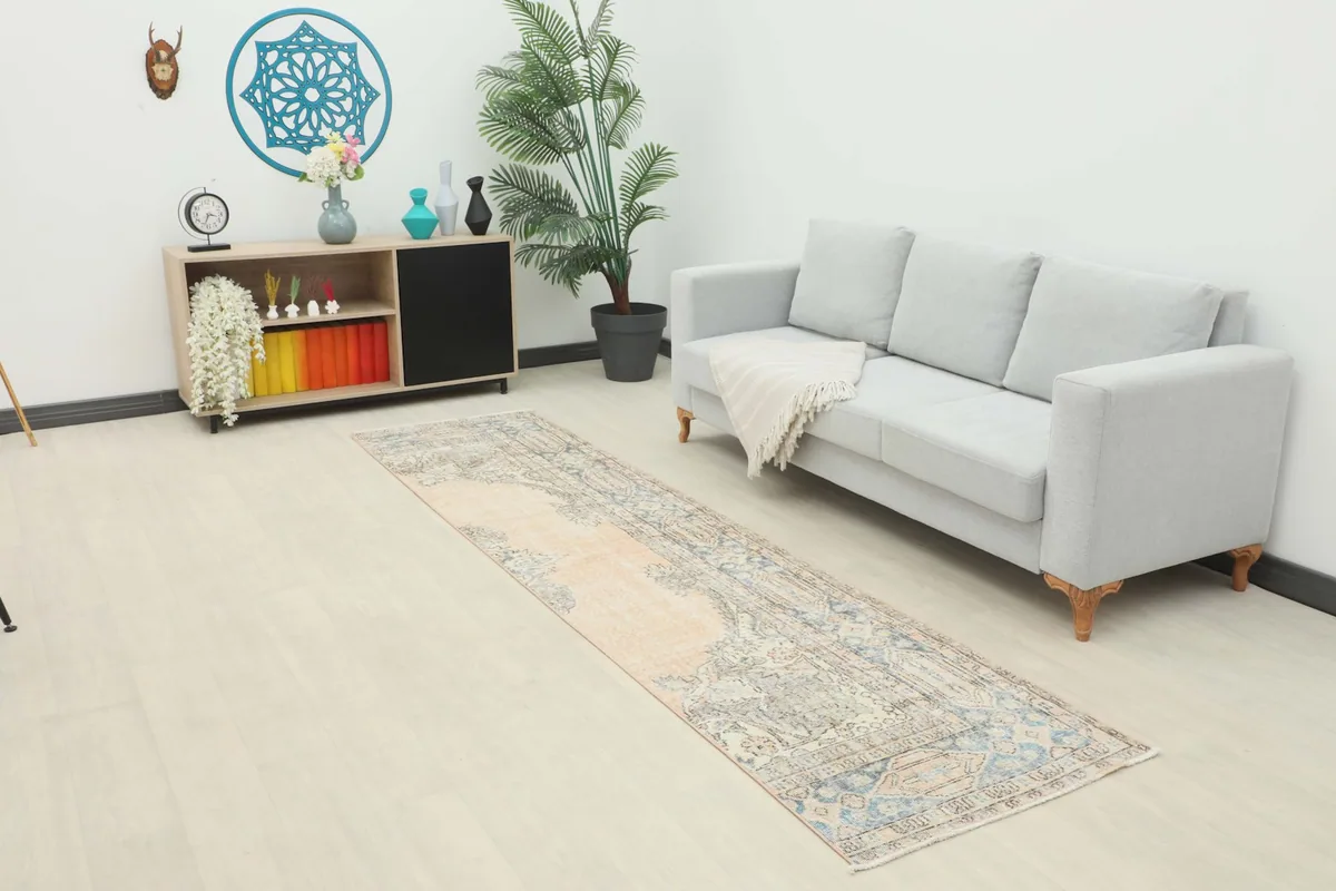 Vintage runner rug displayed in a modern living space with a light gray sofa and wooden cabinet.