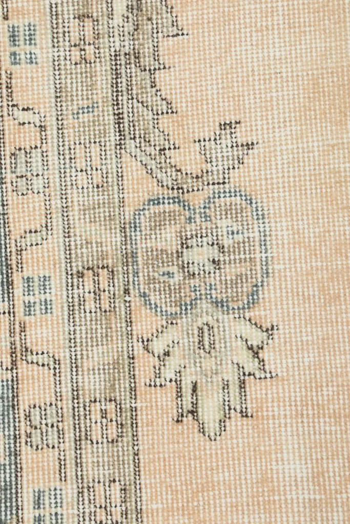 Close-up of a floral motif within the cream field, revealing the hand-knotted texture and pile.