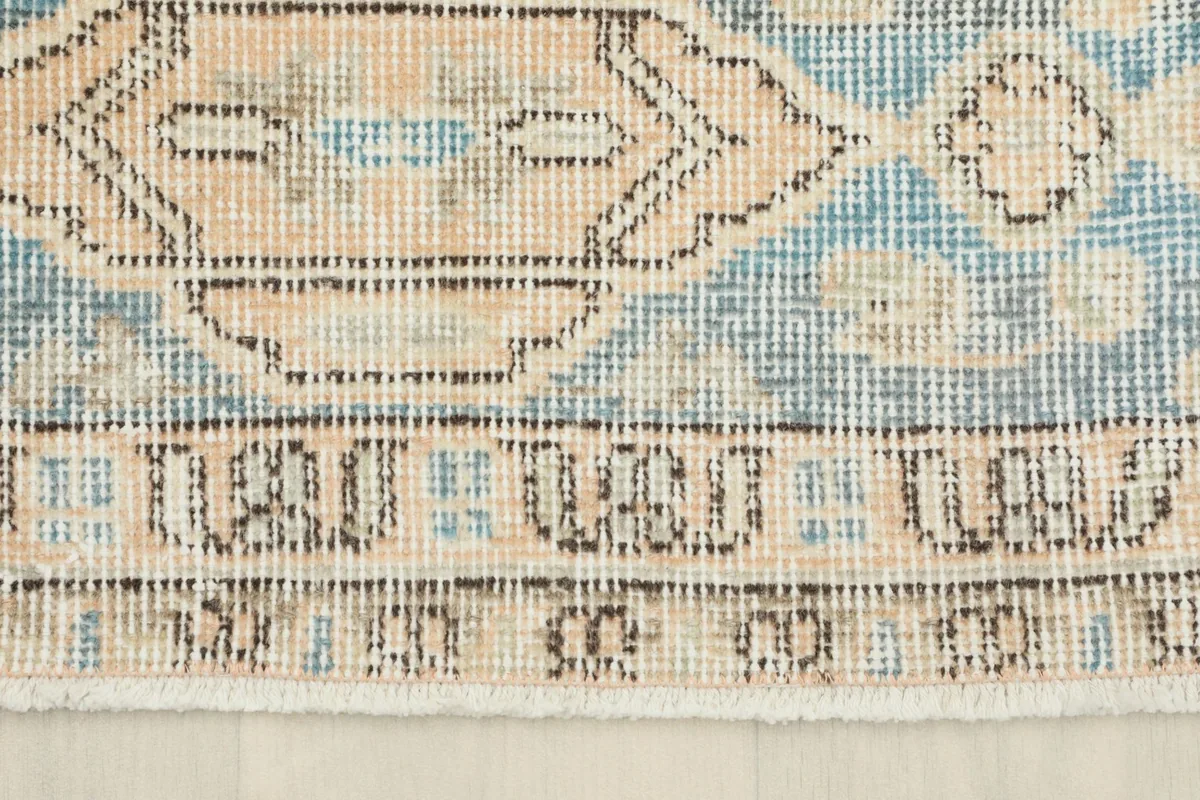Detailed shot of the blue and tan geometric border pattern and the short fringe.